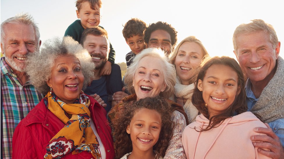 Grupo de pessoas de diversas idades sorrindo para foto