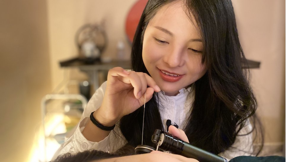 Zhang Meili removes wax from a customer's ear