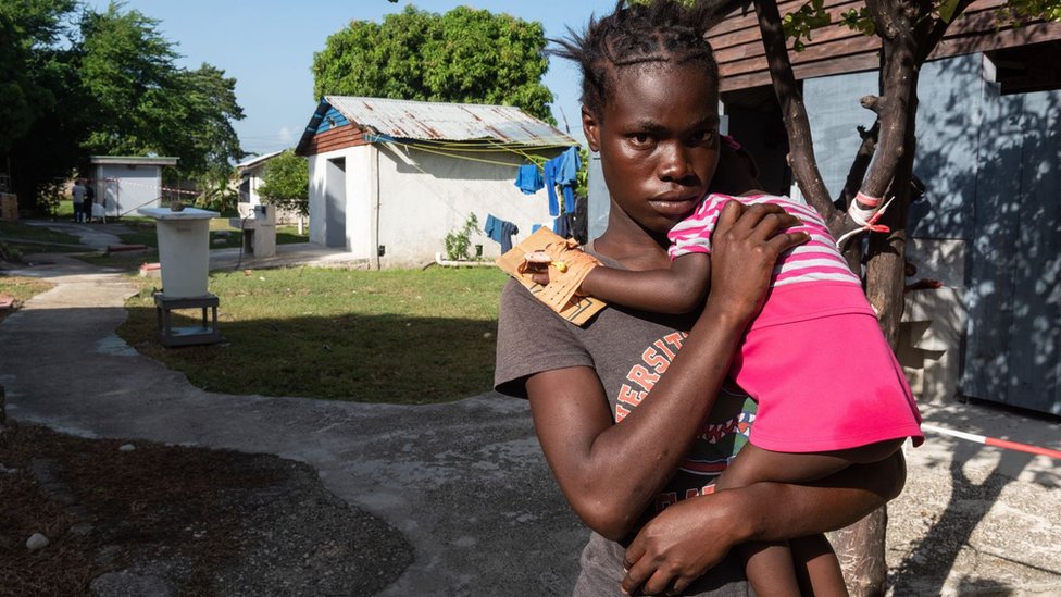 Una mujer carga a una niña