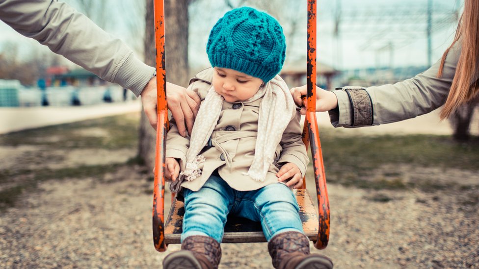 Child on a swing in between her parents