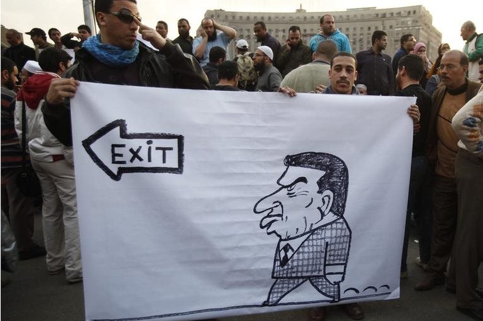 Протестующие держат карикатуру на президента Египта Хосни Мубарака в Каире в 2011 году