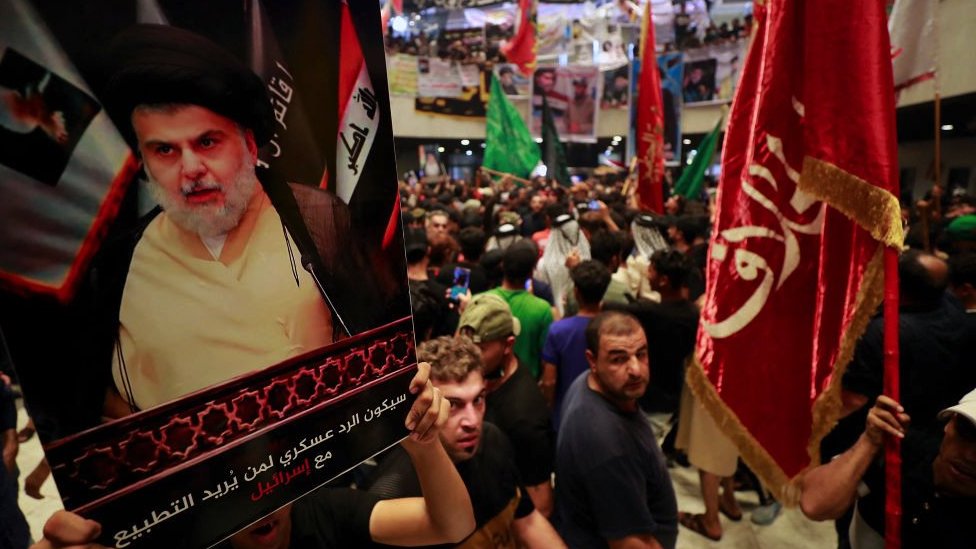 Supporters of Shia cleric Moqtada al-Sadr carry a placard with picture during a 20022 protest in Baghdad