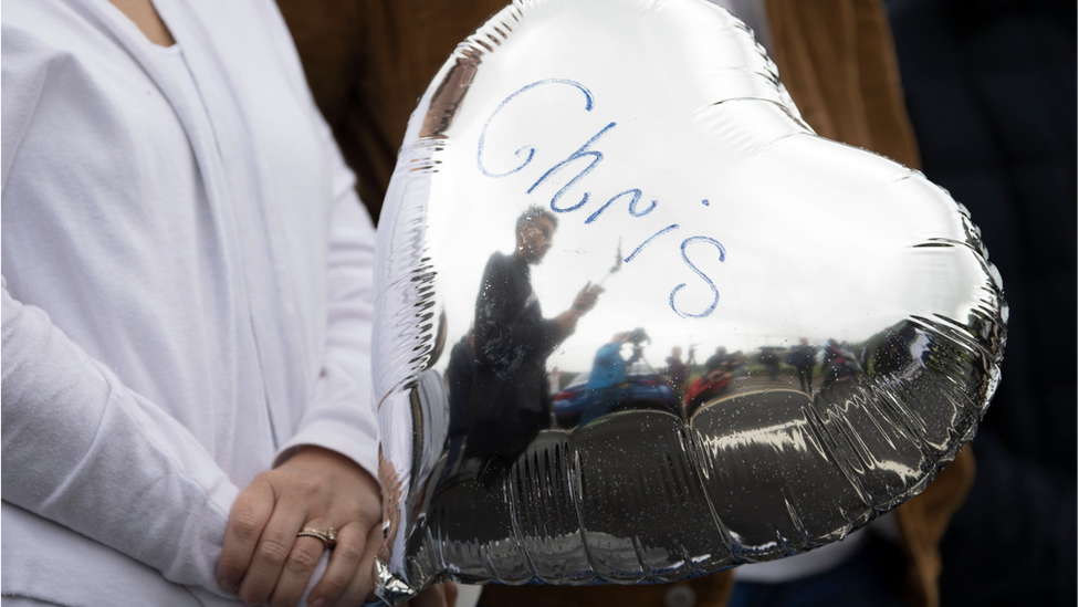 Человек держит воздушный шар с надписью «Крис»