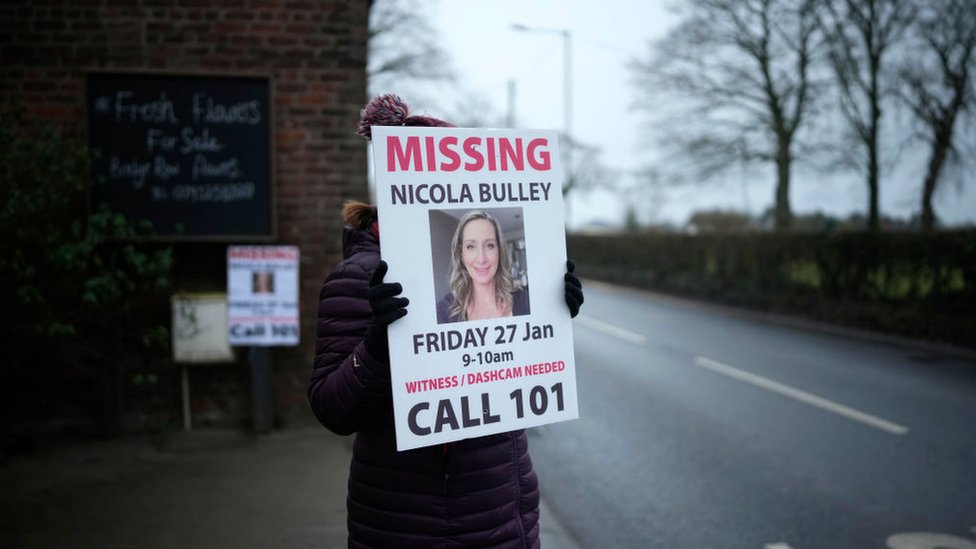 一位女士舉起呼籲公眾就失蹤女子尼古拉·布勒下落提供情報的海報