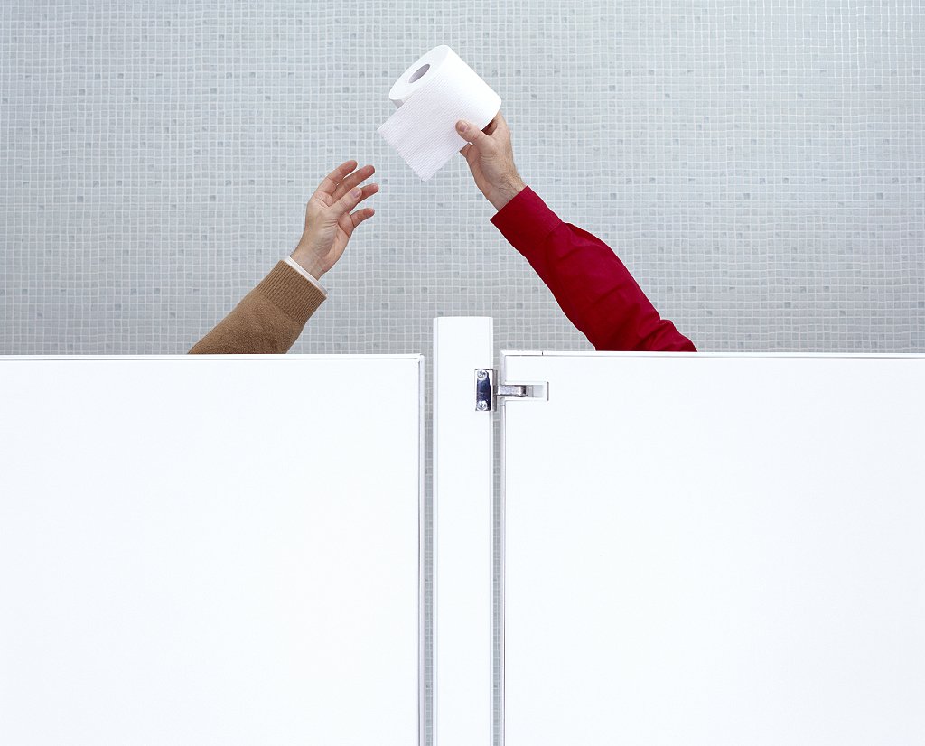 Manos pasándose papel higiénico en baño público