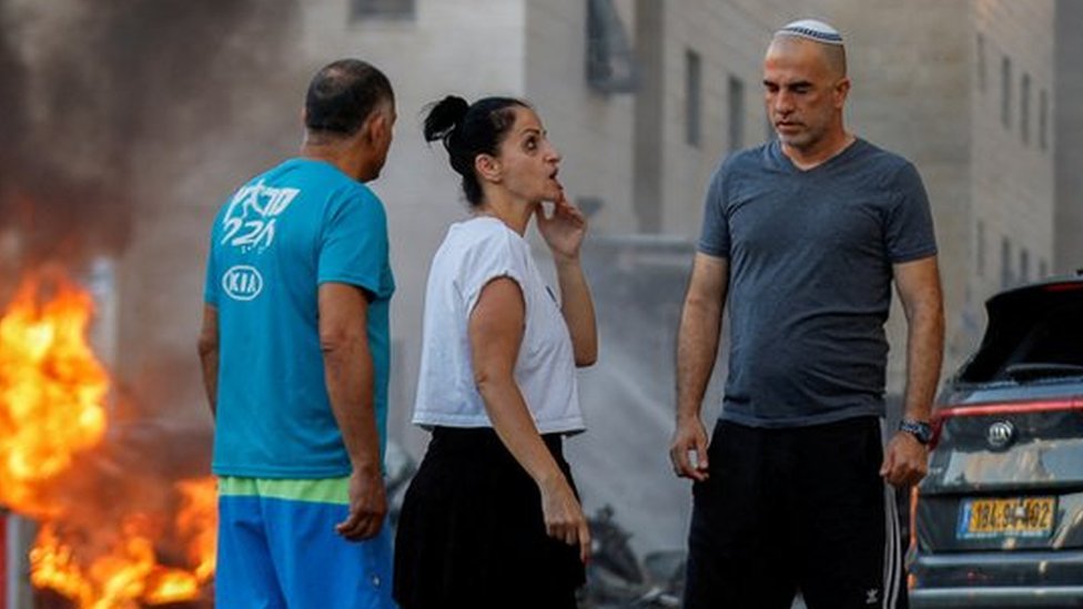 People react near a fire after rockets were launched from the Gaza Strip, in Ashkelon, Israel October 7, 2023.