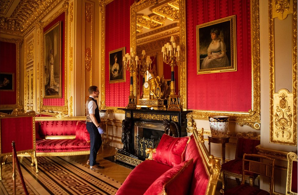 Fjodor stands in a large gold and red state apartment