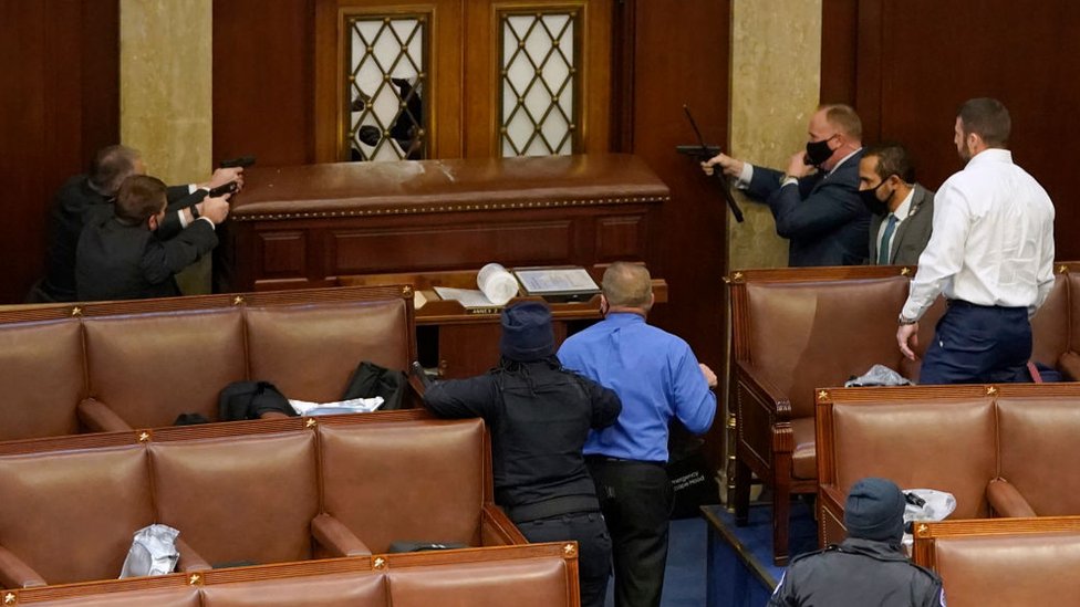 Capitol police point guns at a protester from inside the Senate chamber
