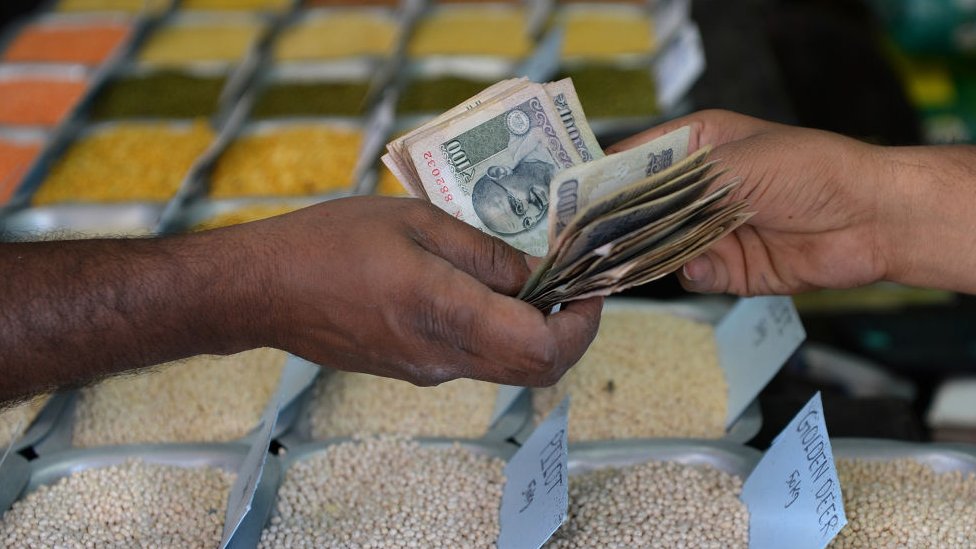 Индийский покупатель передает наличные деньги продавцу продовольственного зерна в оптовом магазине в Бангалоре