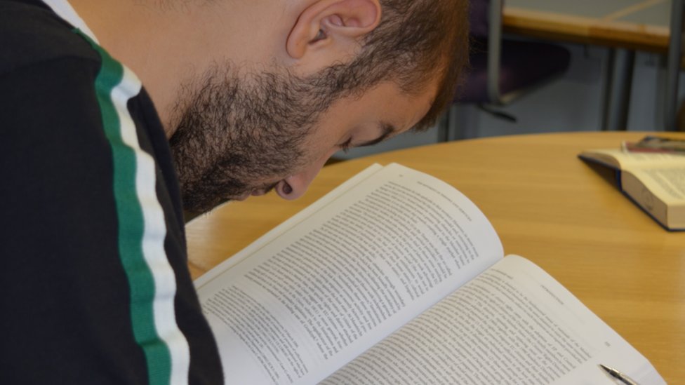 Allan Hennessy debe acercarse a las páginas para poder leer. Allan leyendo.