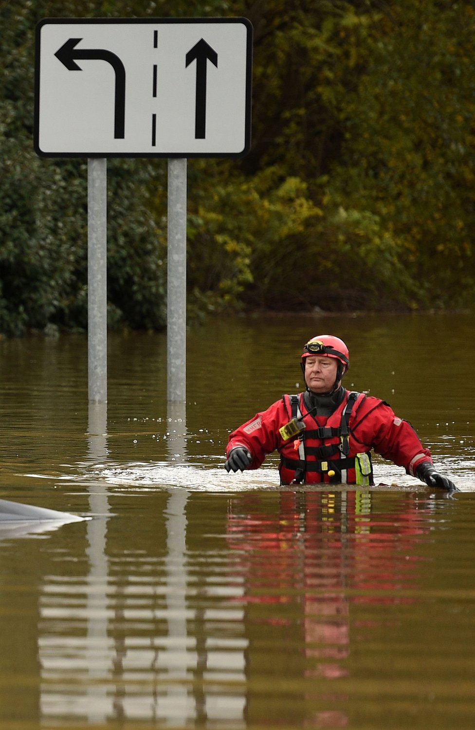 Сотрудник пожарно-спасательной службы пробирается по паводковой воде