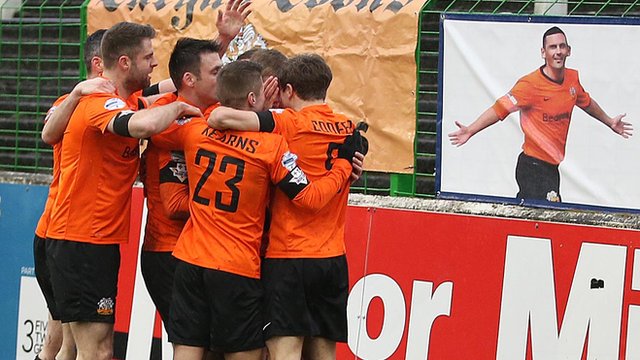 Glenavon players celebrate the opening goal against Glentoran in front of a picture of former player Mark Farren who passed away this week