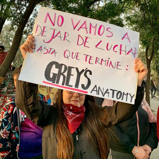 Una mujer sostiene un cartel