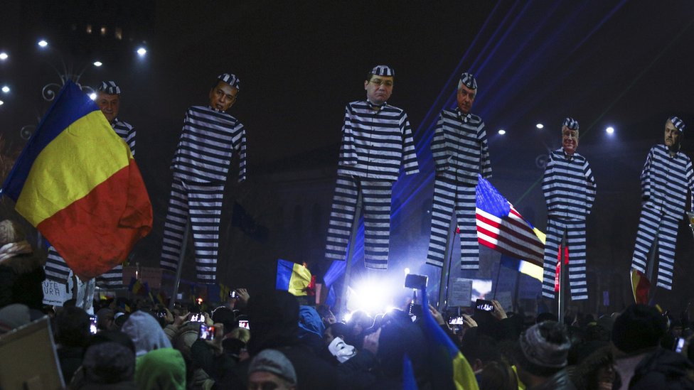 Протестующие в Румынии держат изображения правительственных чиновников