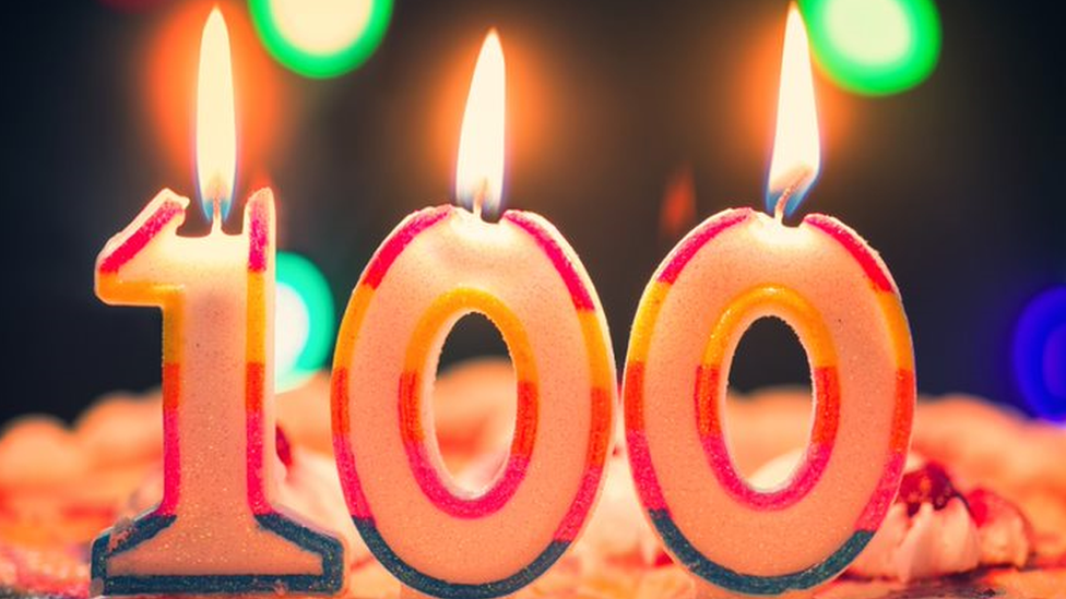 Candles for a 100th birthday, with flames melting the digits
