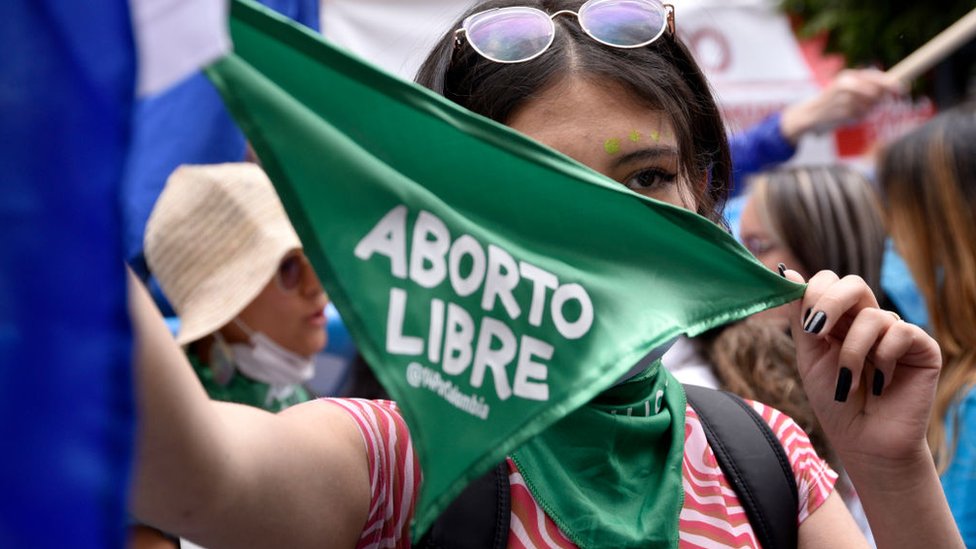 Mujer manifestante con pañuelo verde que dice 