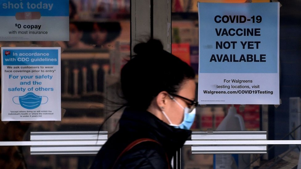 A woman walks past a "Covid-19 vaccine not yet available" sign outside a store in Arlington, Virginia on December 1, 2020