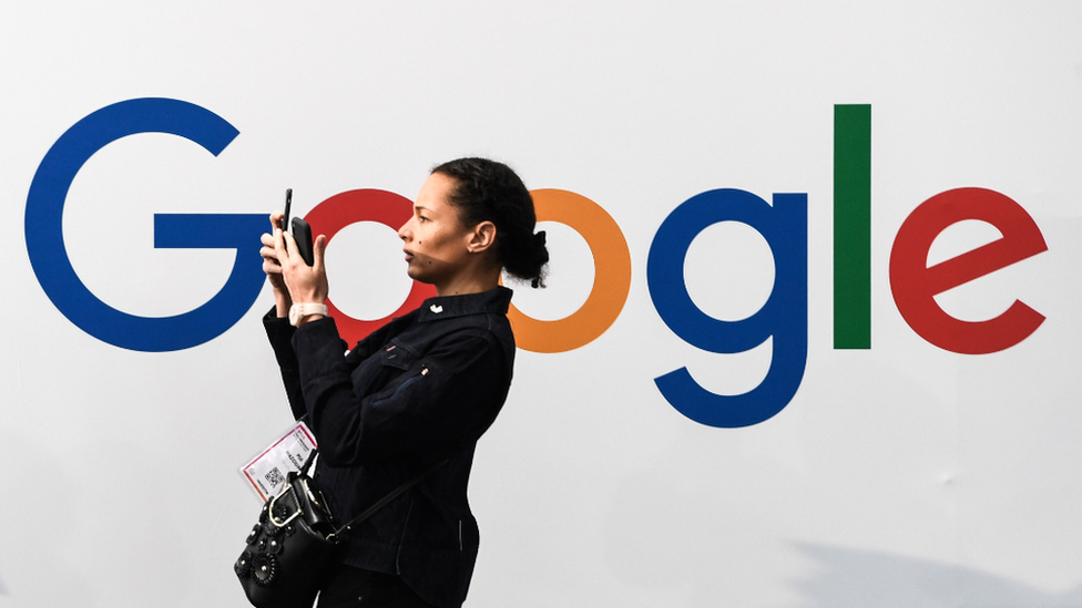 Mujer frente a un letrero de Google