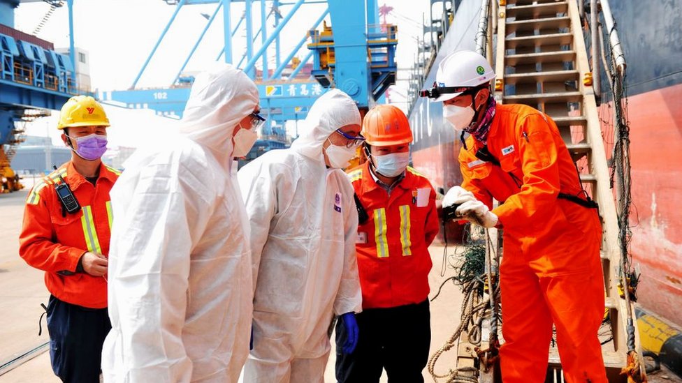 Китайские пограничники проверяют члена экипажа, покидающего судно в контейнерном порту в Циндао