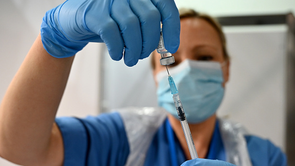 Profissional da saúde segura seringa e ampola com vacina