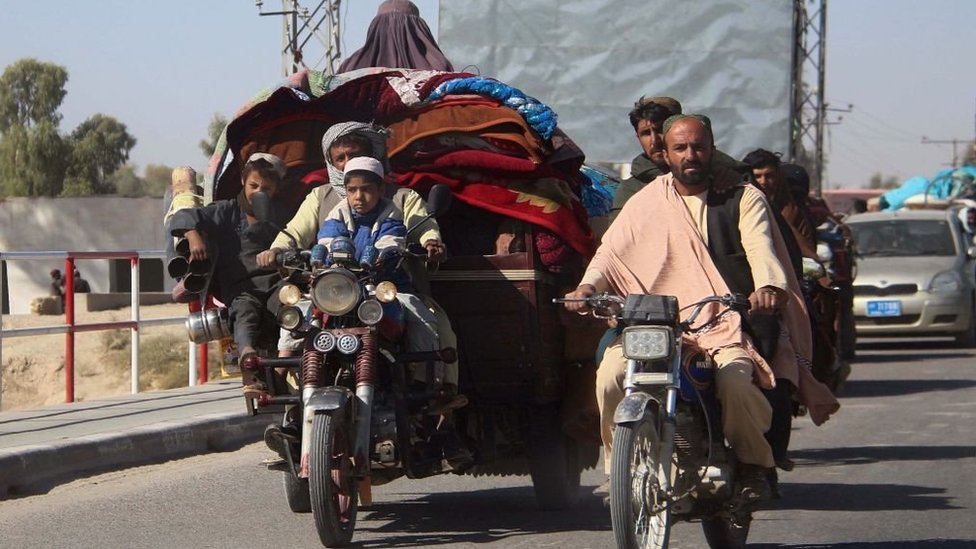 People on motorised vehicles heavily laden with carpets and blankets