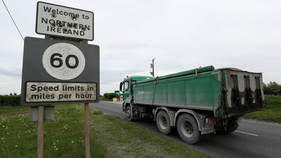 Грузовик проезжает мимо таблички с надписью: Добро пожаловать в Северную Ирландию