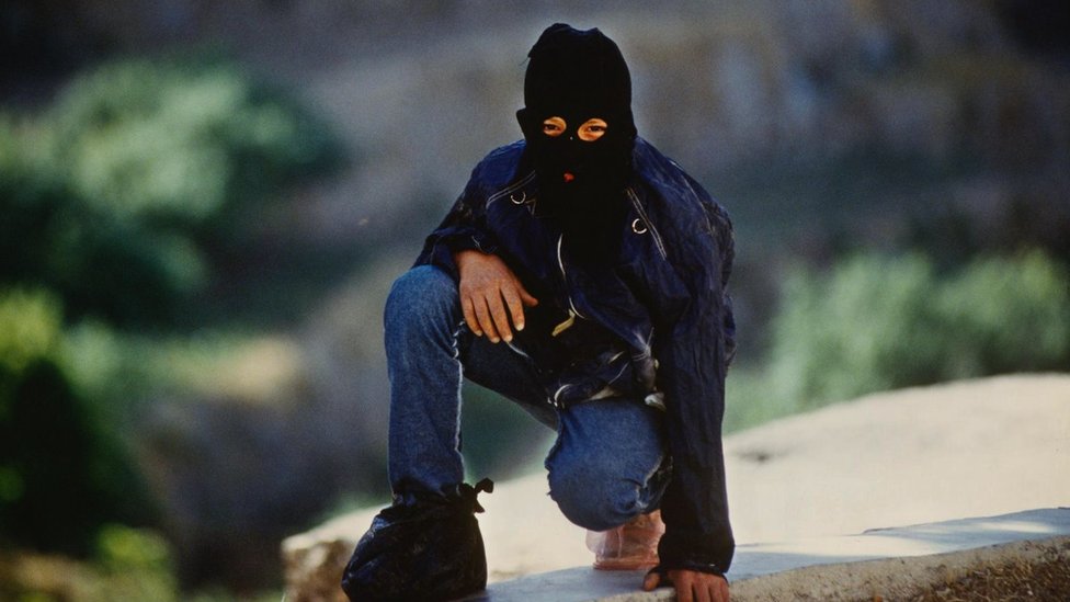 Palestinski borac sa maskom da bi sakrio svoj identitet, na slici patrolira selom na okupiranoj Zapadnoj obali u junu 1989. godine