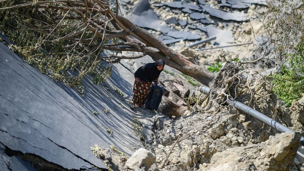 Palu'da yerle bir olmuş bir yolda ilerlemeye çalışan bir kadın