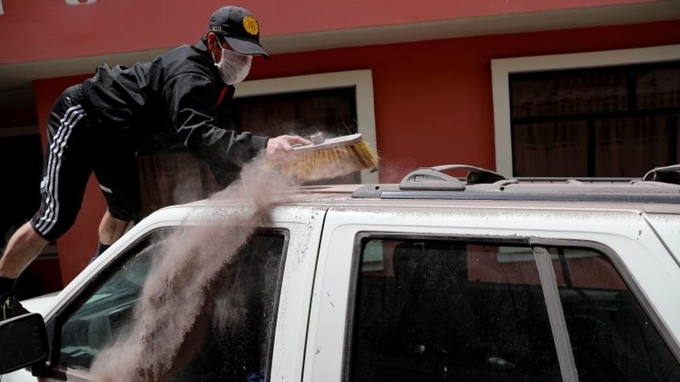 Мужчина очищает свой автомобиль от пепла вулкана Сангай в городе Алауси, провинция Чимборасо, Эквадор, 20 сентября 2020 года