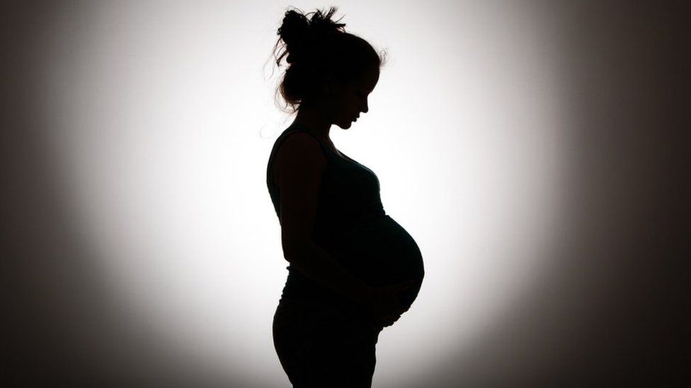 Очертание беременной женщины в тени