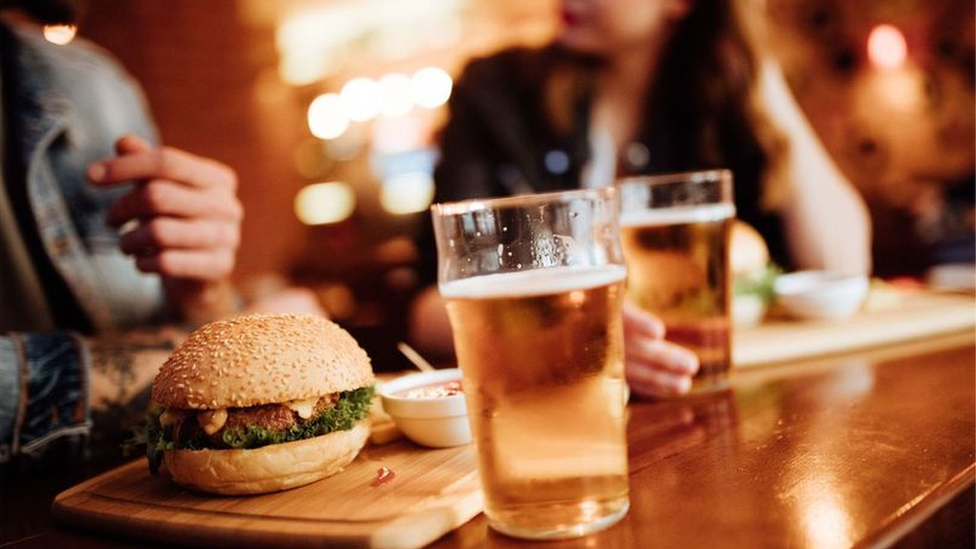 Two people eating burgers in a pub