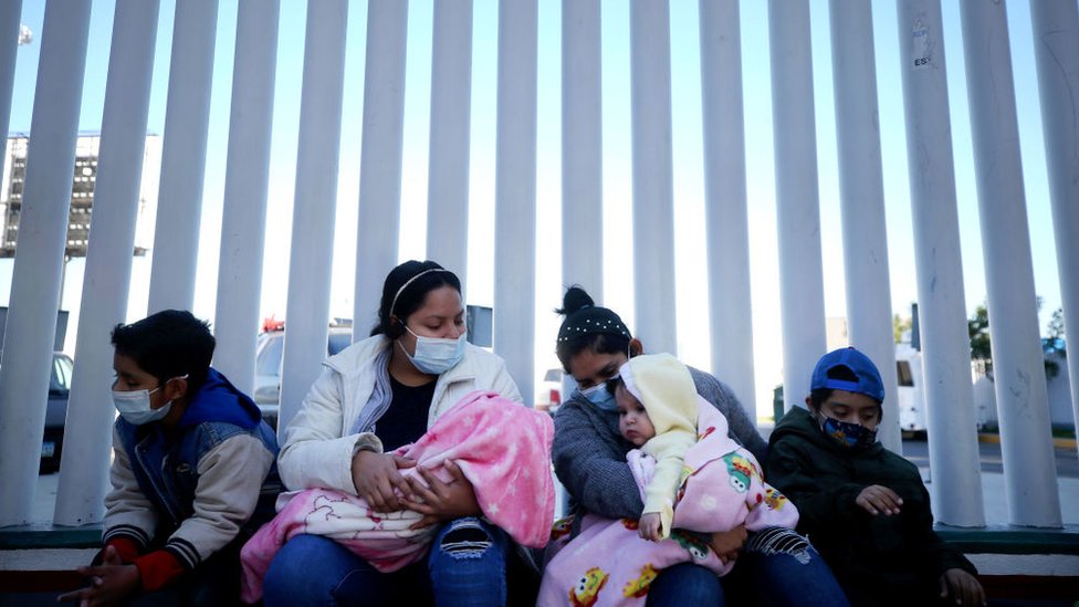 Ciudadanos de El Salvador y Honduras que buscan asilo en Estados Unidos se sientan frente al cruce fronterizo de El Chaparral el 19 de febrero de 2021 en Tijuana, México.