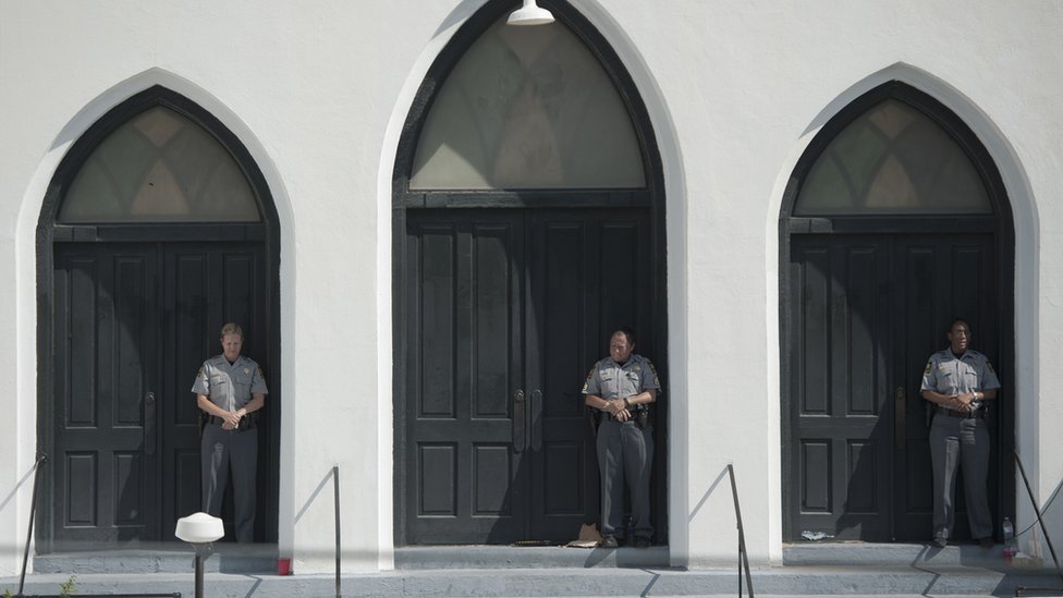 2015-06-21. Полицейские стояли на страже во время воскресной службы в церкви Emanuel AME в Чарльстоне. Колм О'Моллой для BBC News.