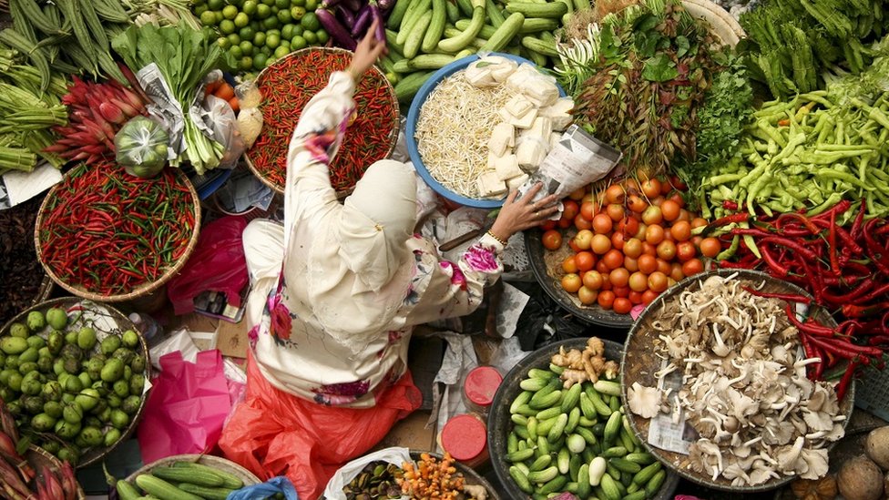 Woman selling fresh vegetables at an Asian market