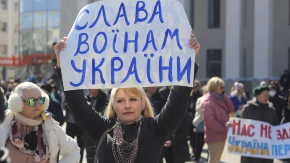 Žena drži transparent "Slava ukrajinskim vojnicima", Herson