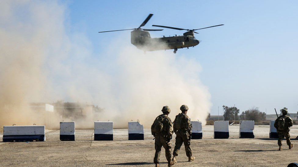 Войска США идут, когда вертолет C-47 Chinook армии США пролетает над деревней Орейдж, к югу от Мосула, 22 февраля 2017 г.