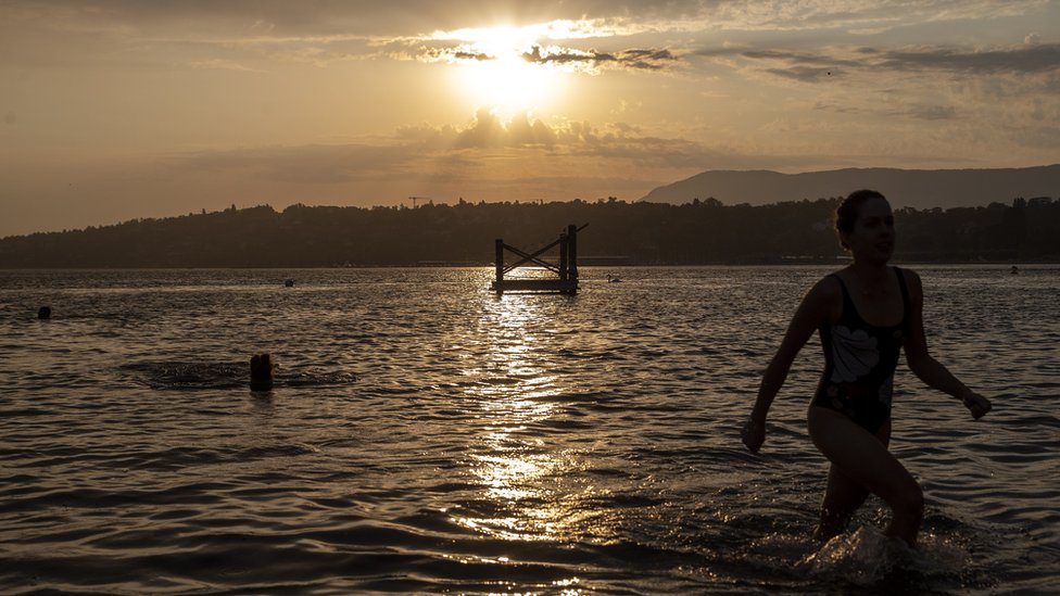 People enjoy bathing at sunrise in the Geneva lake in Geneva, Switzerland