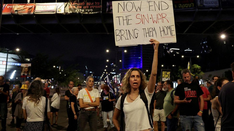 A demonstrator in Tel Aviv holds a sign referencing the Hamas leader Yahya Sinwar