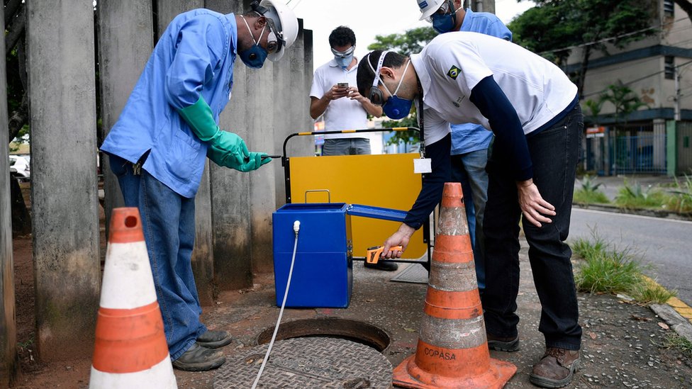 Técnicos tomando pruebas de una alcantarilla en Belo Horizonte, Brasil