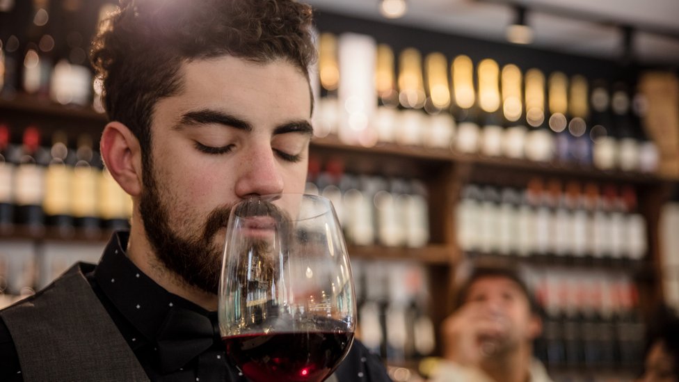 Hombre oliendo una copa de vino.