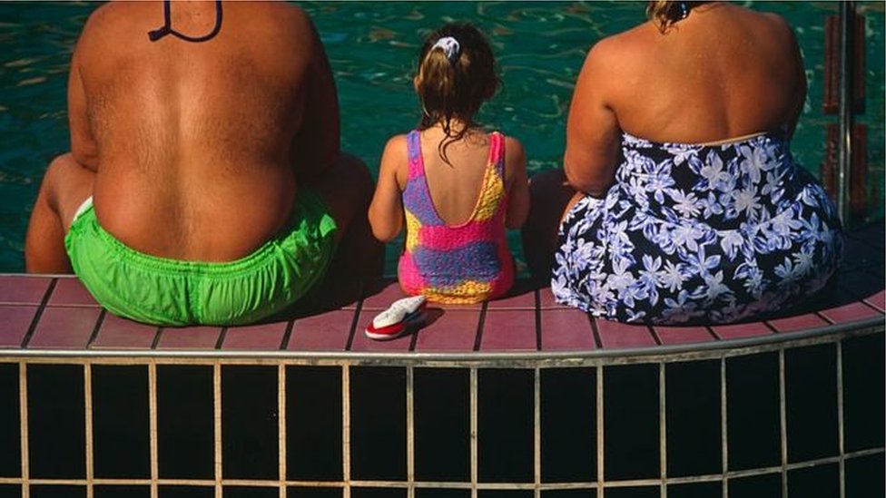 Una niña entre dos personas gordas