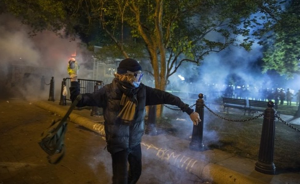 A protesters throws a stone at police (in the background) in Washington DC. Photo: 31 May 2020