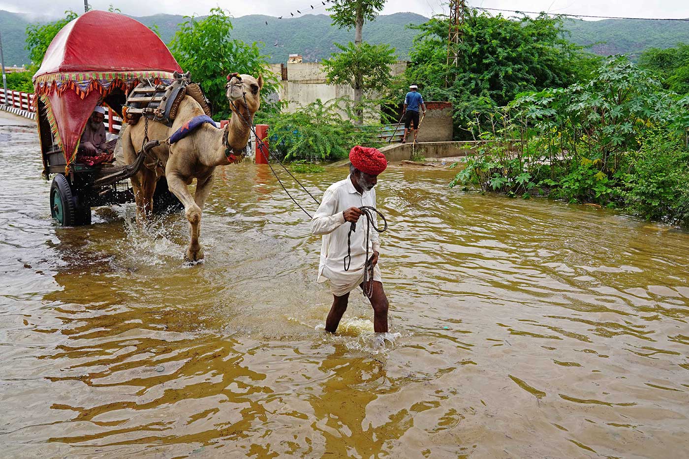 A man and his camel wade across a flooded street after heavy monsoon rains in Pushkar, in India's Rajasthan state - 10 July 2023