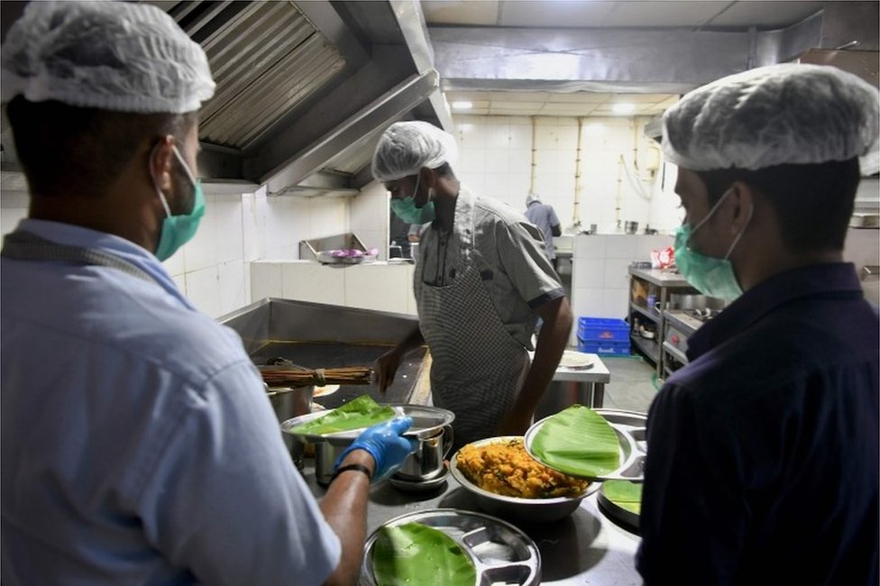 Сотрудники Индийской железнодорожной корпорации общественного питания и туризма (IRCTC) носят маски в качестве превентивной меры против распространения вспышки коронавируса COVID-19, когда они готовят еду для клиентов в ресторане на железнодорожном вокзале Бангалора 4 марта. 2020