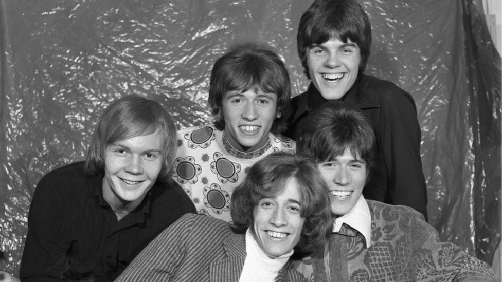 The Bee Gees за кулисами Top of the Pops, где-то между 1967 и 1969. Задний ряд слева-справа: Колин Петерсен; Морис Гибб и Винс Мелуни. Передний ряд слева направо: Робин Гибб и Барри Гибб.