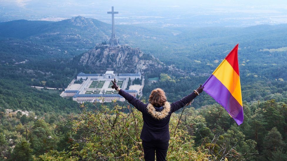 Mujer con la bandera republicana viendo el Valle de los Caídos