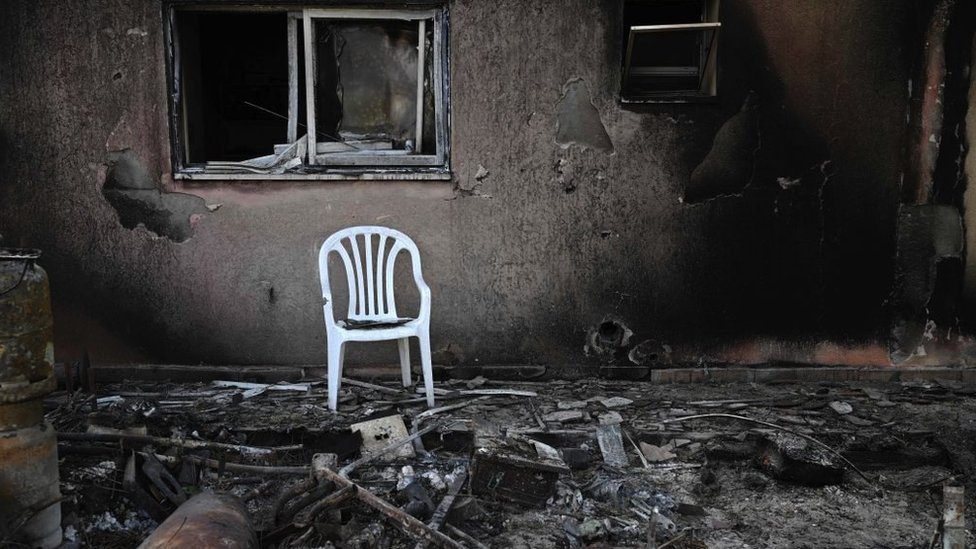 A plastic chair outside a burned-out house