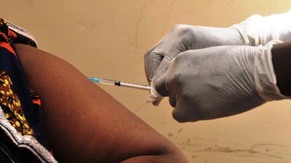 Manos con guantes quirúrgicos administrando una vacuna contra el ébola.