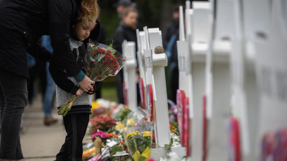 Niño colocando flores en memorial de muertos por tiroteo