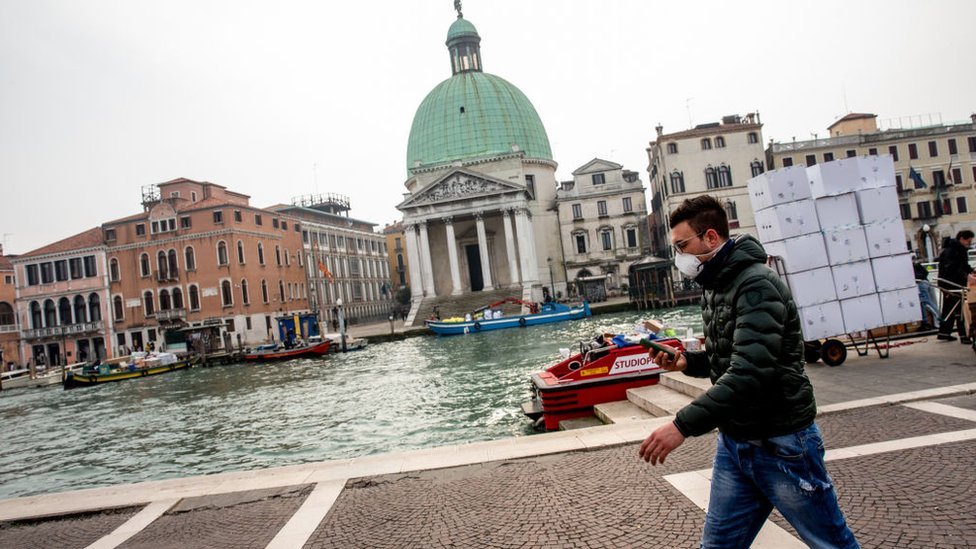 Hombre caminando con mascarilla en Venecia.